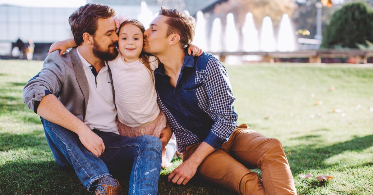 Two gay dads kissing their adopted daughter